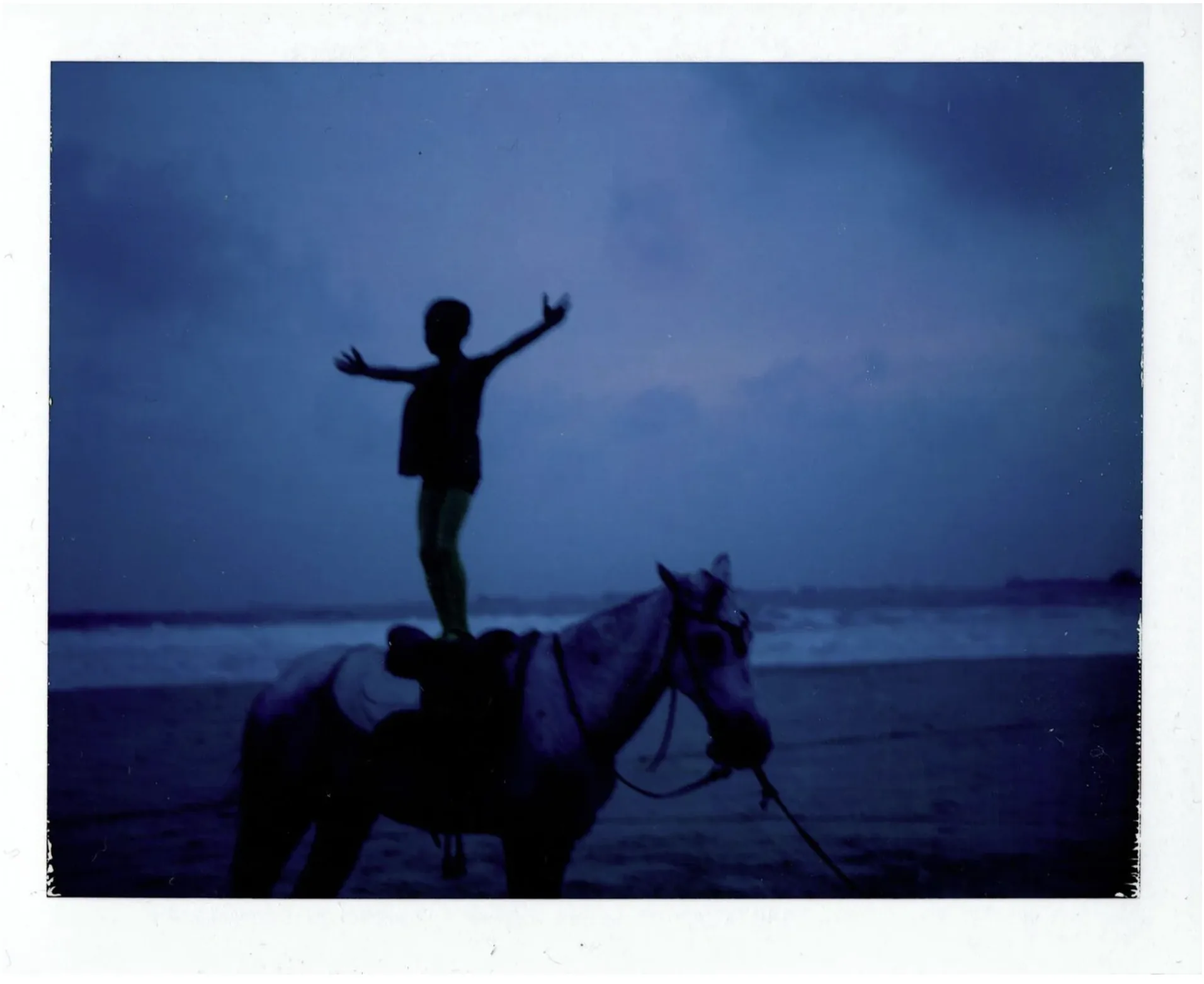 Ijó — boy standing on horse at beach, dusk